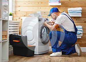 Working man plumber repairs washing machine in laundry photo