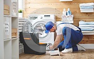 Working man plumber repairs washing machine in laundry photo