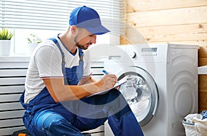 Working man plumber repairs washing machine in laundry