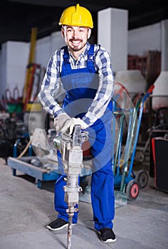 working man practicing his skills with pneumatic drill at workshop