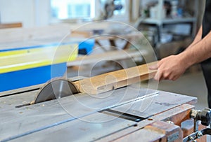 Working man using circular saw at carpentry shop