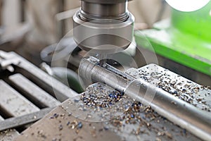 In a working milling machine, a hole is drilled in a metal part and metal fragments are splashed