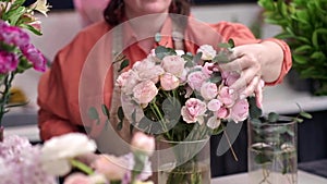 Working in modern floral shop, creative female business owner arranges stunning bouquet pink blooms