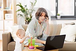 Working mother with baby calling on smartphone