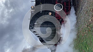 Working old German steam locomotive with smoke on railway station.Vertical video