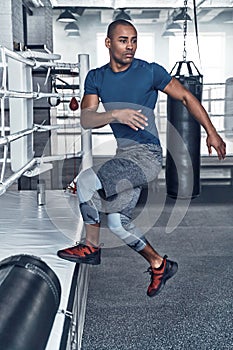 Working out. Handsome young African man in sport clothing jumping while exercising in the gym