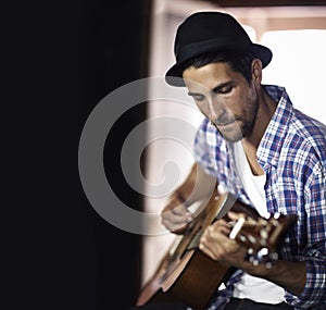 Working out a new song. A handsome young musician playing a guitar.