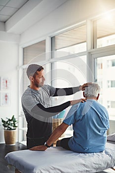 Working out the stiffness in his neck. a young male physiotherapist assisting a senior patient in recovery.