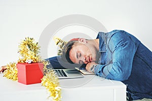 Working over the festive season is such a drag. a handsome young businessman sleeping on his desk while working in his