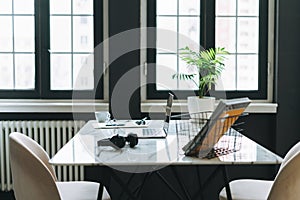 Working place with cup of coffee, notes, open laptop, eye glasses and smartphone on white marble table in the dark modern office