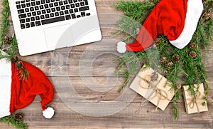 Working place laptop Christmas decoration red hat gifts flat lay
