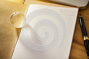 Working place with pen glass globe and notebook papers on wooden table