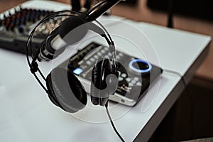 Working place of radio host. Close up of headphones, microphone and sound mixing desk on the table in recording studio