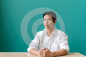 Portrait of asian businessman smiling and looking at camera with smile while sitting at his working place of blue wall.