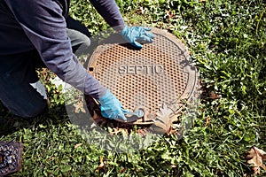 A working plumber opening septic system tank. Copy space