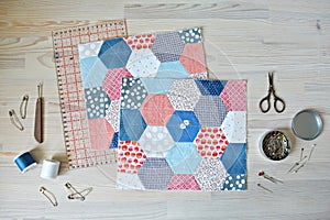 Working process: hexagon quilt, threads, retro scissors, pins, metal jar, quilting ruler and seam ripper