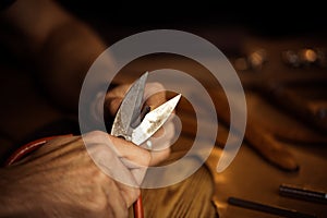 Working process of the leather belt in the leather workshop. Man holding crafting tool and working. Tanner in old photo