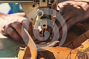 Working process of leather craftsman. Tanner or skinner sews leather on a special sewing machine, close up photo