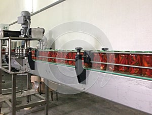 Working process of the production of Preserved red hot chili peppers on cannery. Pasteurization of cans. Movement on the conveyor photo