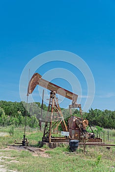 Working pump jack pumping crude oil at oil drilling site in rural USA