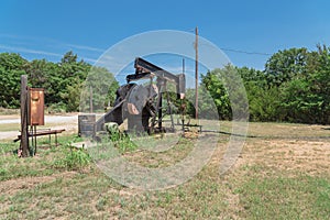 Working pump jack pumping crude oil at oil drilling site in rural USA