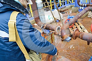 Working repairs rusty pipes and flanges at petrochemical pla