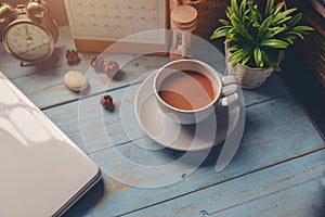 Working space at home,Cup of Coffee with Desktop Calendar 2019,laptop,clock and pot of tree on blue wooden desk.Urban Lifestyle