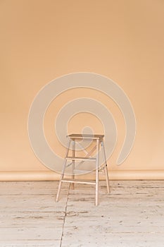 The working space of the photo studio with a beige paper background and chair.