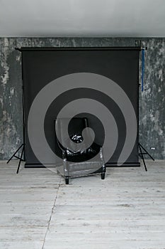 The working space of the photo studio with a black paper background and black armchair.