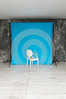 The working space of the photo studio with a blue paper background and chair.