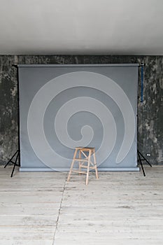 The working space of the photo studio with a grey paper background and chair.
