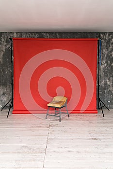 The working space of the photo studio with a red paper background and chair.