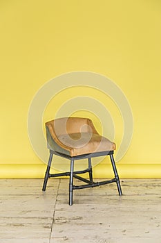 The working space of the photo studio with a yellow paper background and chair.
