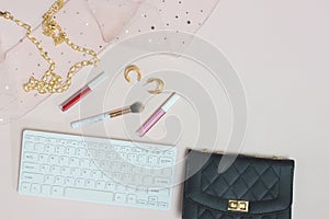 Working space for women with keyboard, lips and black bag over the pink background.