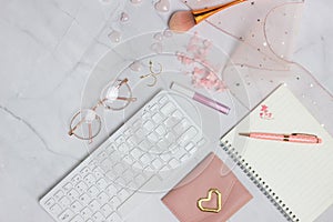 Working space for women with keyboard, notebook, pen and flowers over the marble background.