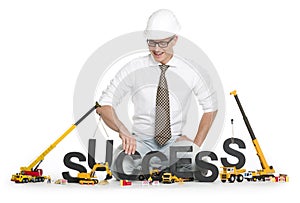 Working on success: Businessman buildinging success-word.