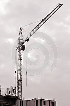 Working tall cranes inside place for with tall buildings under construction against a clear blue sky. Crane and building working