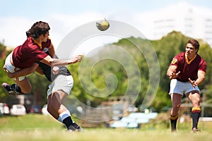 Working together for stronger unity. Shot of a young rugby player executing a pass mid-tackle.