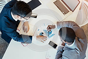 Working together to make the business grow. High angle shot of two young focused businessman making notes while looking