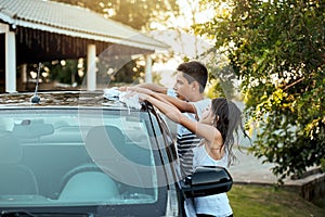 Working together to make the work go quicker. two cheerful children washing their parents car together outside during