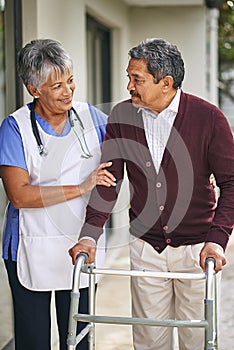 Working towards regaining complete mobility. a nurse going for a walk with her senior patient and his walker outside.