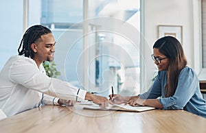 Working through it. two businesspeople going through paperwork together in an office.