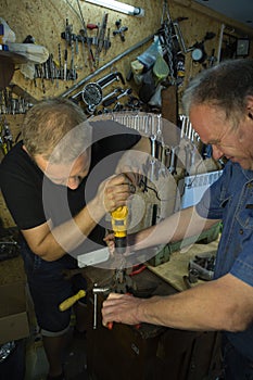 Working with a vise and drill. The master uses a drill. Portrait of a master at work. The young man works with an assistant