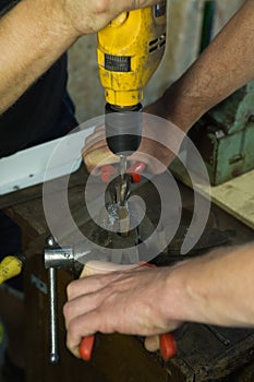 Working with a vise and drill. The master uses a drill. Portrait of a master at work. The young man works with an assistant