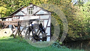 Working water mill wheel turning by the power of water at small lake pond rural idyll scene