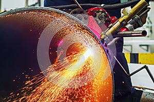 Working welder cuts metal and sparks fly. Gas cutting of large diameter pipes with acetylene and oxygen. Industrial