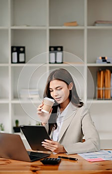 Working woman concept a female manager attending video conference and holding tablet, smatrphone and cup of coffee