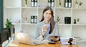 Working woman concept a female manager attending video conference and holding tablet, smatrphone and cup of coffee in office