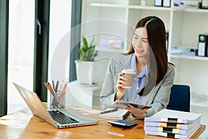 Working woman concept a female manager attending video conference and holding tablet, smatrphone and cup of coffee in office