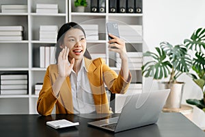 Working woman concept a female manager attending video conference and holding tablet, smatrphone in modern office